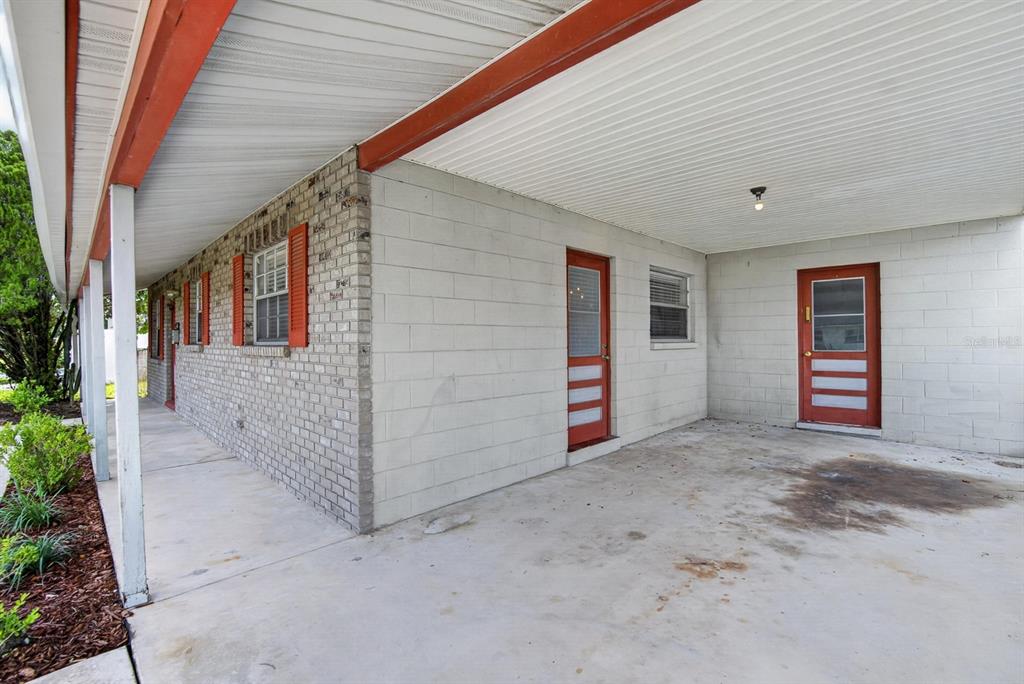 A concrete carport with two red doors and a brick exterior wall — 403 ALMA DRIVE, BRANDON, FL