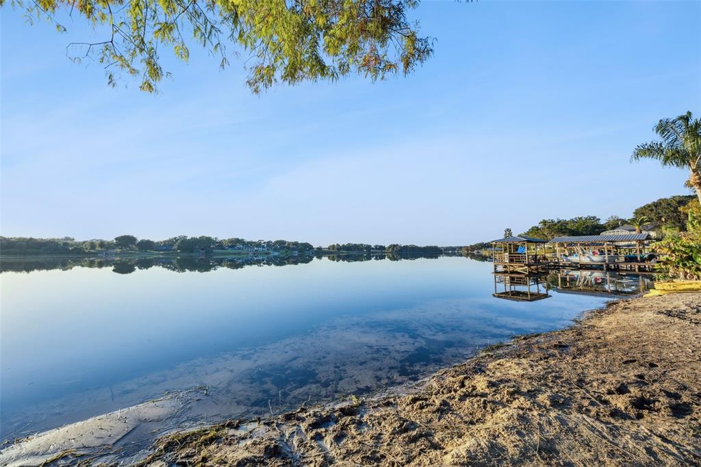 A sandy shoreline overlooks a calm lake with a wooden boat dock and covered slips — E CROOKED LAKE DRIVE, EUSTIS, FL