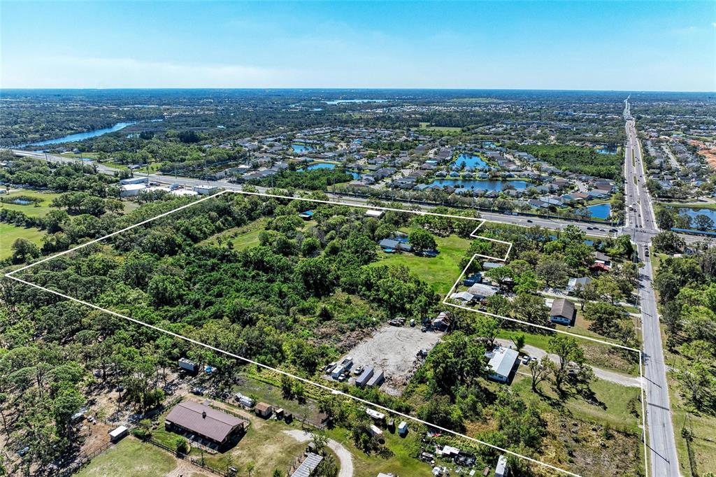 An aerial view shows a large, partially wooded plot of land with several structures — 4609 44TH AVENUE E, BRADENTON, FL