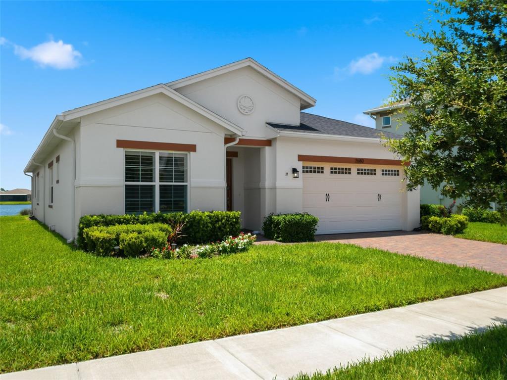 A single-story house with a white stucco exterior, a two-car garage, and a landscaped yard — 2680 REDBLUSH TERRACE, ST CLOUD, FL