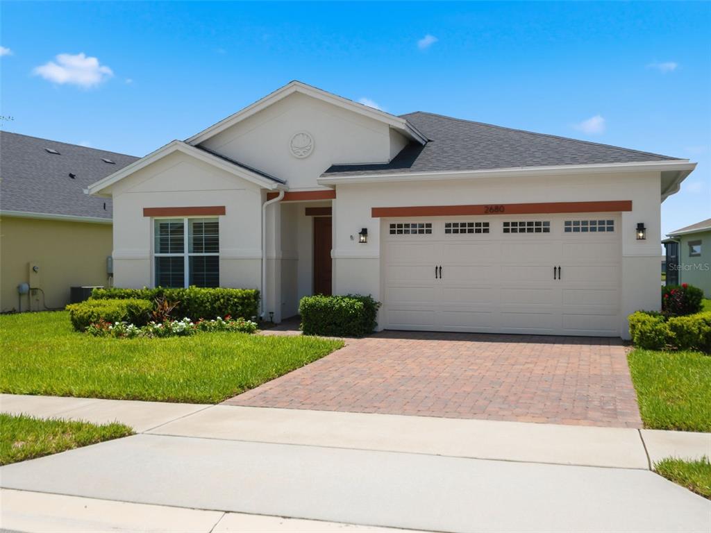 A single-story house with a white stucco facade, a two-car garage, and a brick driveway — 2680 REDBLUSH TERRACE, ST CLOUD, FL