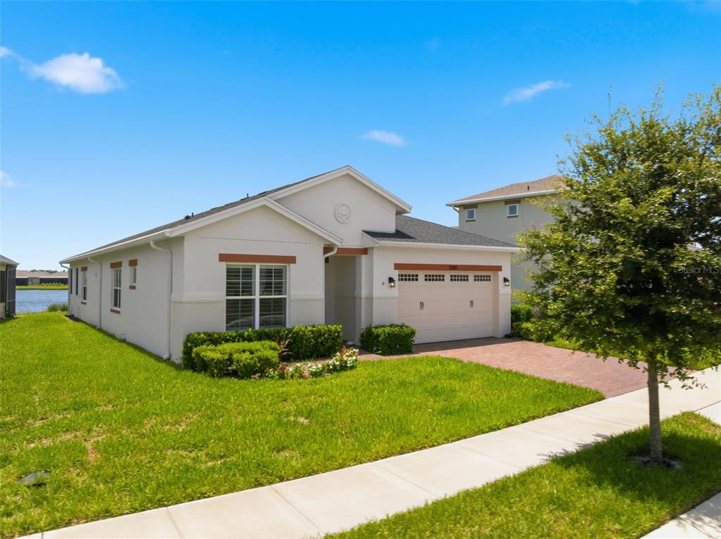 A single-story house with a white stucco exterior, a two-car garage, and a grassy lawn — 2680 REDBLUSH TERRACE, ST CLOUD, FL
