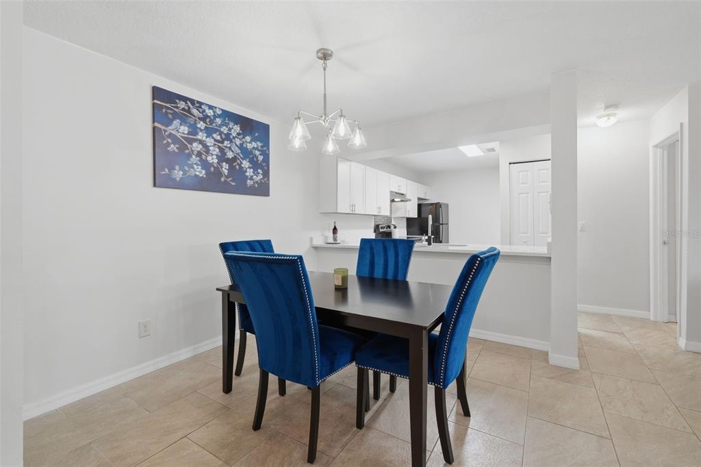 A dining area with a dark table, four blue velvet chairs, and a kitchen pass-through — 648 KENWICK CIRCLE UNIT 102, CASSELBERRY, FL
