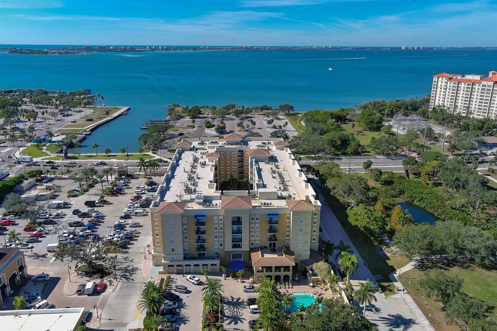 An aerial view shows a large multi-story hotel building with a pool near the water — 1064 N TAMIAMI TRAIL UNIT 1433, SARASOTA, FL