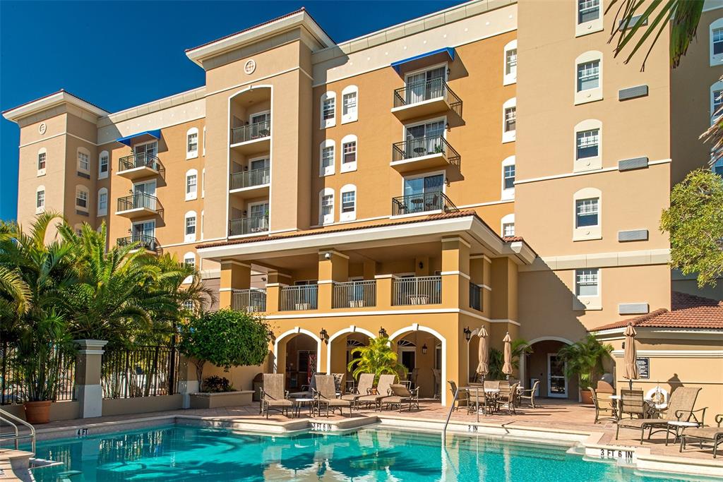 A multi-story tan hotel building features balconies and a swimming pool in the foreground — 1064 N TAMIAMI TRAIL UNIT 1433, SARASOTA, FL