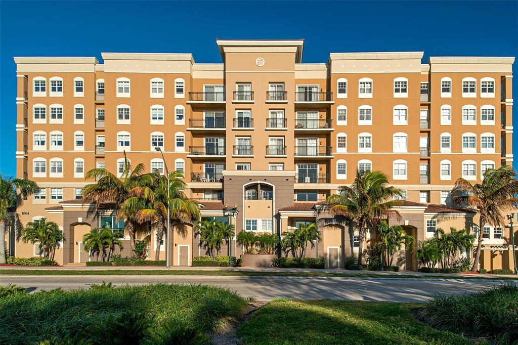 A multi-story apartment building with tan stucco walls, balconies, and palm trees in front — 1064 N TAMIAMI TRAIL UNIT 1433, SARASOTA, FL