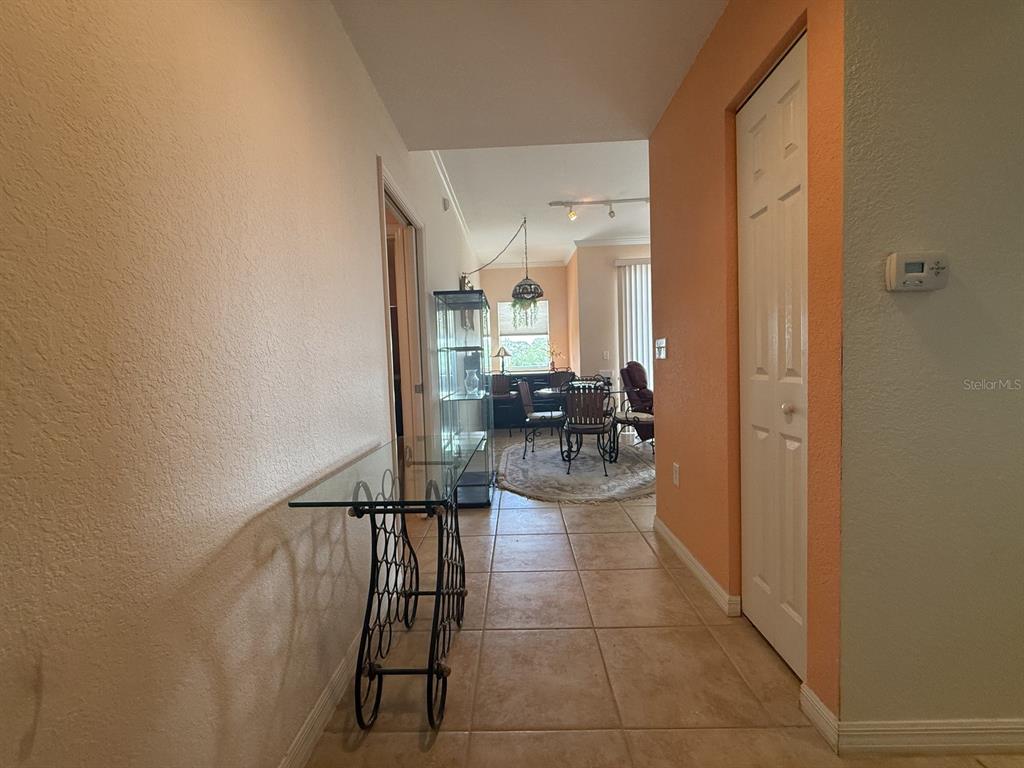 A tiled hallway leads to a dining area with a glass display cabinet and chandelier — 1064 N TAMIAMI TRAIL UNIT 1433, SARASOTA, FL