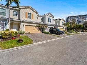 A multi-story townhouse with a beige exterior, a paved driveway, and a black SUV parked outside — 3953 BLACK OLIVE LANE, HOLLYWOOD, FL