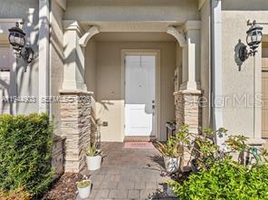 A covered entryway features stone-accented columns, a white front door, and two wall-mounted lanterns — 3953 BLACK OLIVE LANE, HOLLYWOOD, FL