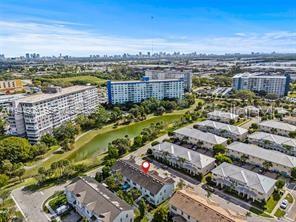 An aerial view shows a residential complex with multi-story buildings, townhouses, and a central pond — 3953 BLACK OLIVE LANE, HOLLYWOOD, FL