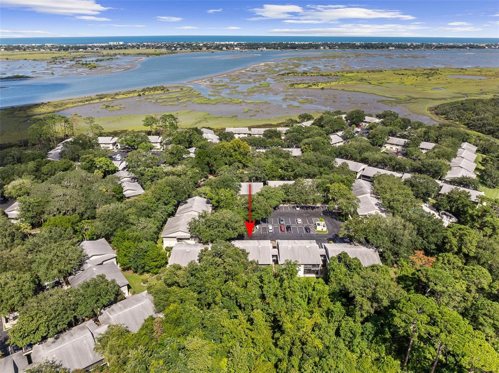 An aerial view shows a residential complex with gray roofs surrounded by trees and marshland — 35 NAVARRA COURT UNIT 35, ST AUGUSTINE, FL