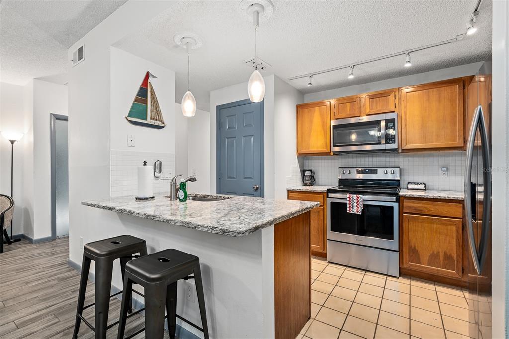 A kitchen features wood cabinets, granite countertops, stainless steel appliances, and a breakfast bar — 35 NAVARRA COURT UNIT 35, ST AUGUSTINE, FL