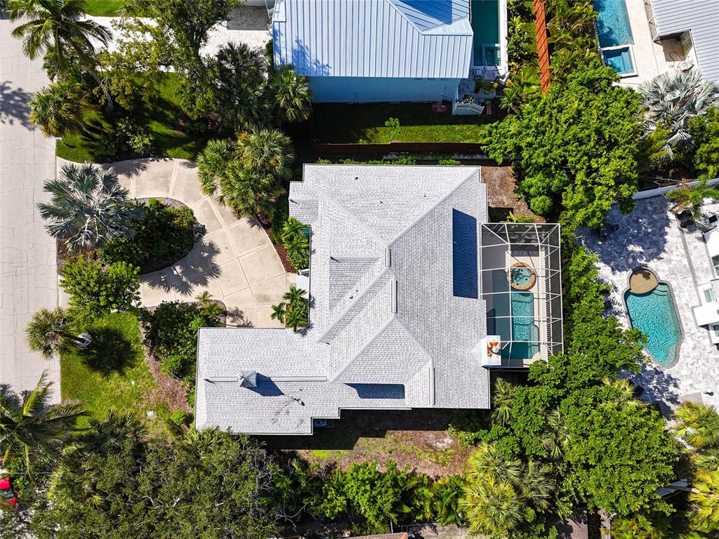 An aerial view shows a house with a gray roof, a pool cage, and landscaping — 5334 CALLE FLORIDA, SARASOTA, FL