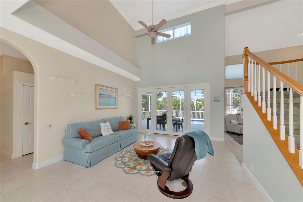 A living room features a vaulted ceiling, a blue sofa, a recliner, and a staircase — 5334 CALLE FLORIDA, SARASOTA, FL