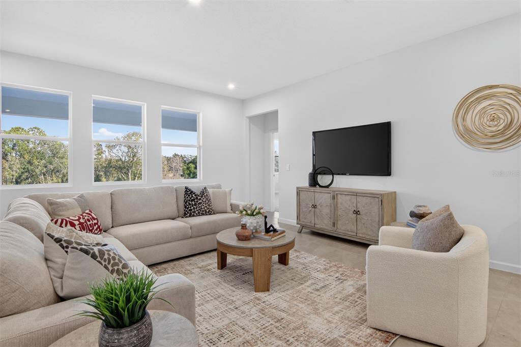 A living room features a beige sectional sofa, a round coffee table, and a television — 304 FREE RANGE DRIVE, GROVELAND, FL
