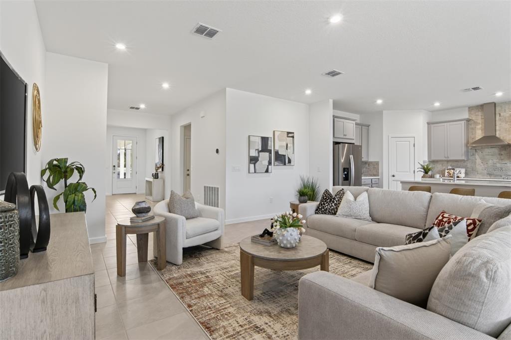 A living room features light-colored furniture, a patterned area rug, and an open-concept kitchen — 304 FREE RANGE DRIVE, GROVELAND, FL