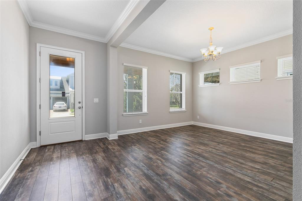 A bright room features dark wood-look flooring, light gray walls, a chandelier, and a glass-paneled door — 9211 NEHER STREET, ORLANDO, FL