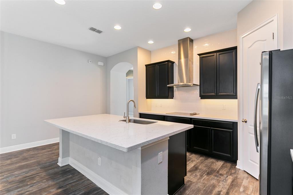 A modern kitchen features a white quartz island, black cabinets, and stainless steel appliances — 9211 NEHER STREET, ORLANDO, FL