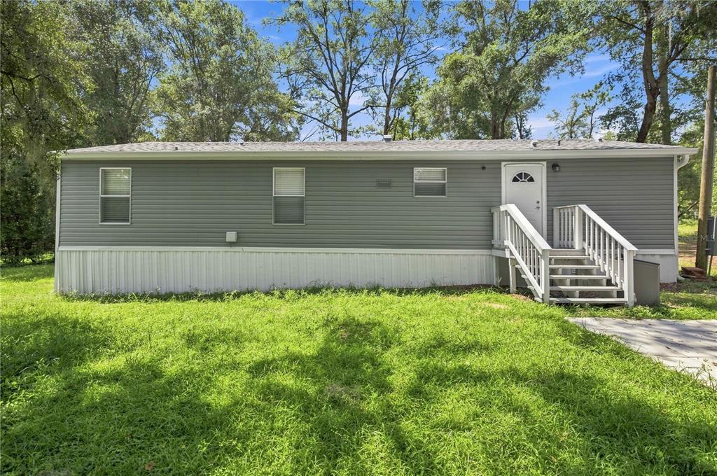 A gray manufactured home with white skirting and a wooden staircase leading to the door — 2545 SE 178TH STREET, SUMMERFIELD, FL