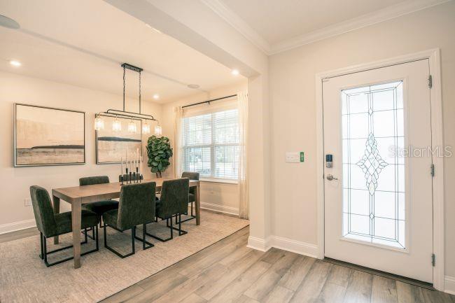 A dining area with a wooden table and dark chairs sits beside a front entryway door — 3418 MONARCH WAY, GREEN COVE SPRINGS, FL