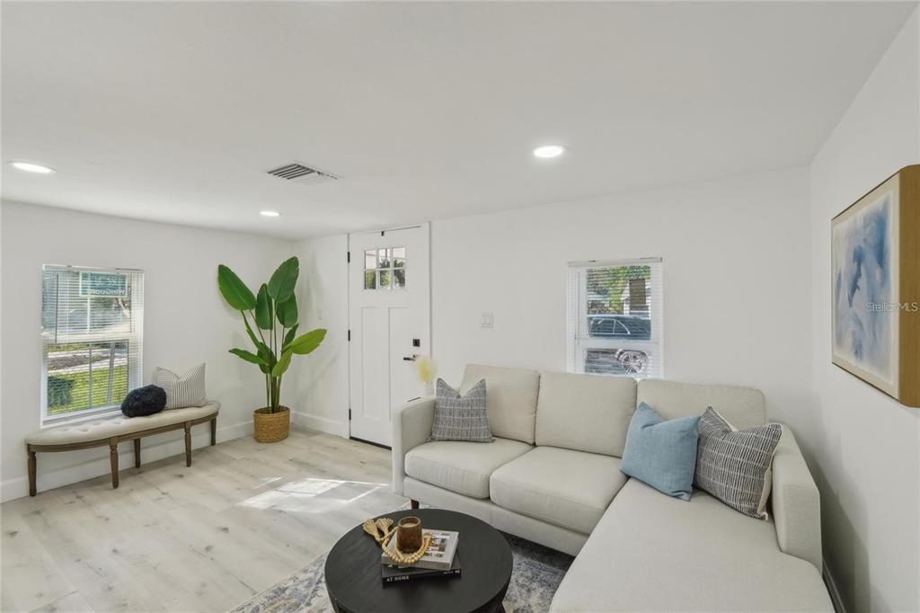 A living room features a white sectional sofa, a round coffee table, and a bench — 2111 E ELLICOTT STREET, TAMPA, FL