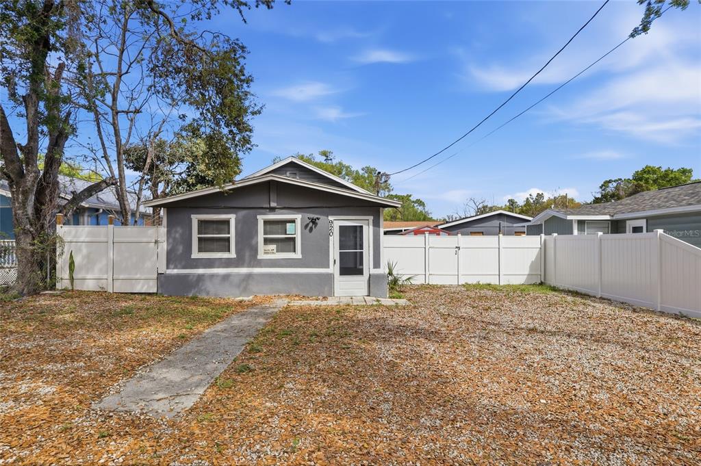 A gray detached house with a white fence stands on a gravel lot — 920 E ANNIE STREET, TAMPA, FL