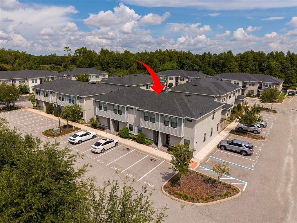 An aerial view shows a multi-unit residential building with gray siding and dark shingled roofs — 4787 TERRA ESMERALDA DRIVE, KISSIMMEE, FL