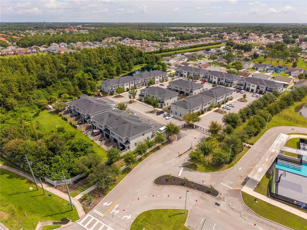 An aerial view shows a residential townhouse complex with parking lots and a nearby pool — 4787 TERRA ESMERALDA DRIVE, KISSIMMEE, FL