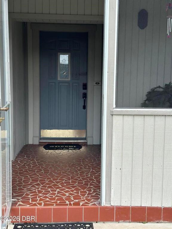 A blue front door with a metal kickplate opens onto a tiled entryway porch — 31109 DEAL DRIVE, MOUNT PLYMOUTH, FL