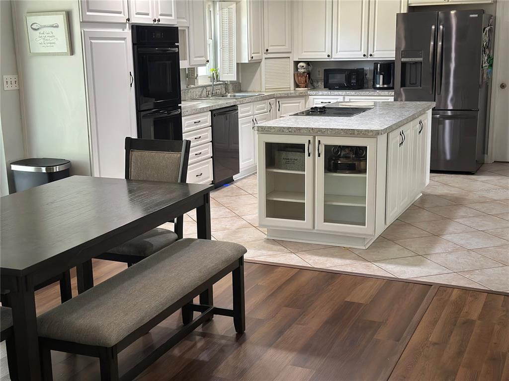 A kitchen features white cabinets, a central island with a cooktop, and dark wood flooring — 31109 DEAL DRIVE, MOUNT PLYMOUTH, FL