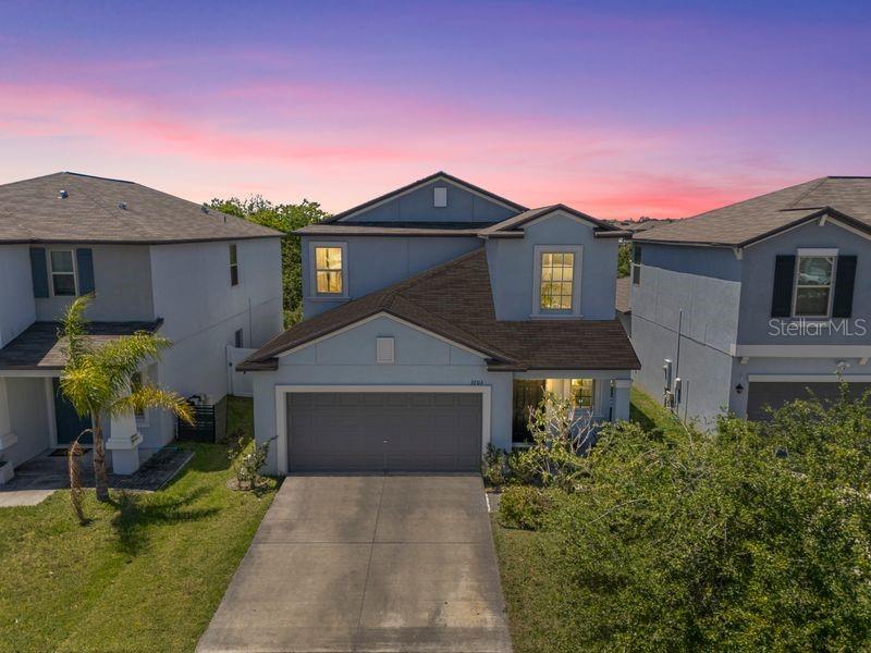 A two-story suburban house with a gray stucco exterior, a two-car garage, and a lawn — 3703 GLOBE THISTLE DRIVE, TAMPA, FL