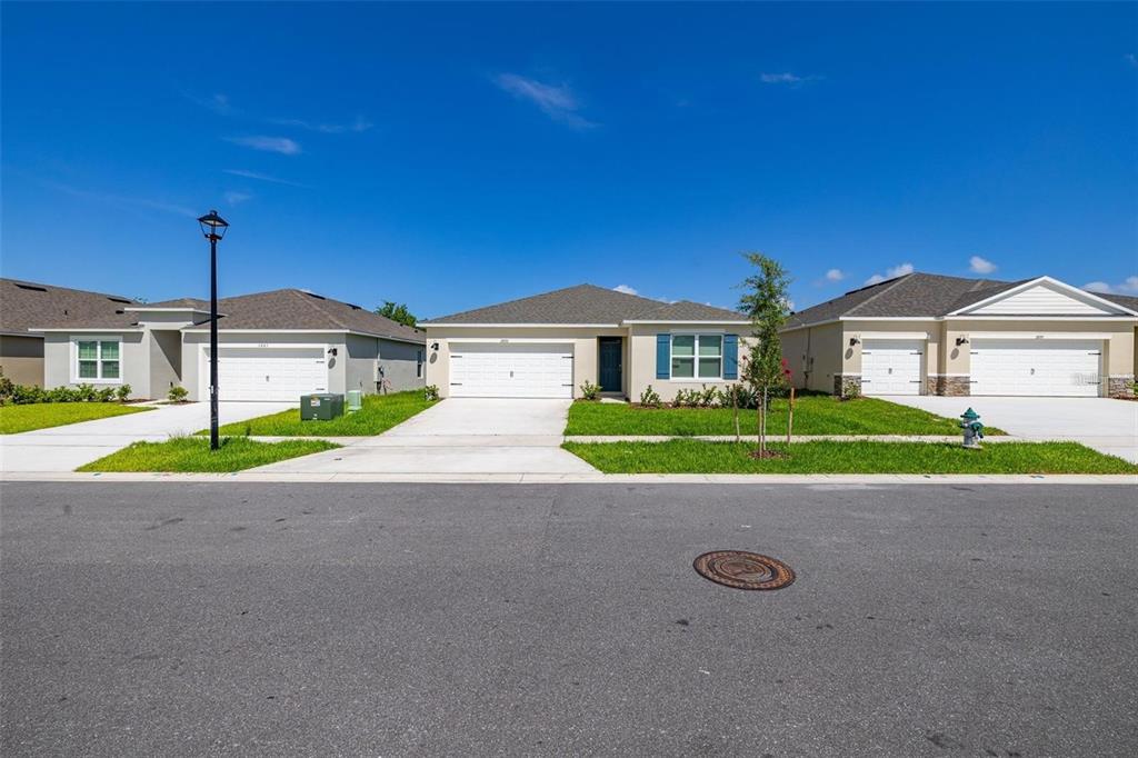 A street-level view shows three modern single-story suburban houses with driveways and manicured lawns — 2893 HOUSE FINCH ROAD UNIT A, HARMONY, FL