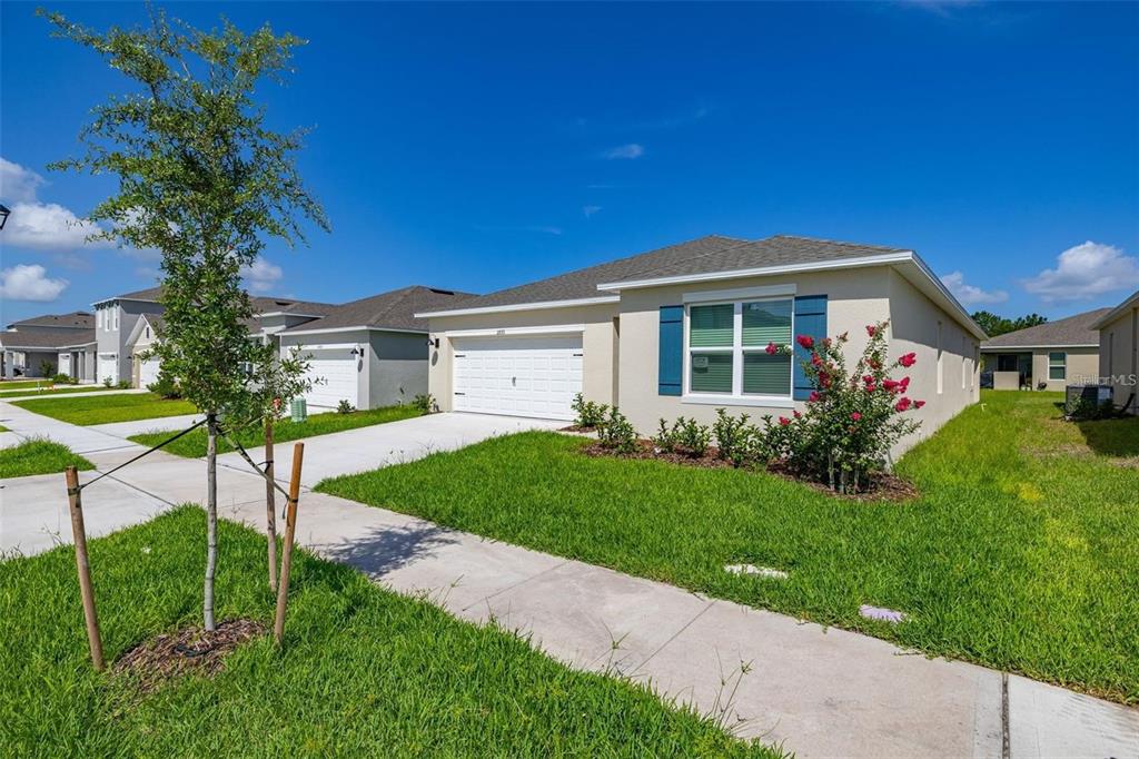 A single-story suburban house with a white garage, blue shutters, and a front lawn — 2893 HOUSE FINCH ROAD UNIT A, HARMONY, FL