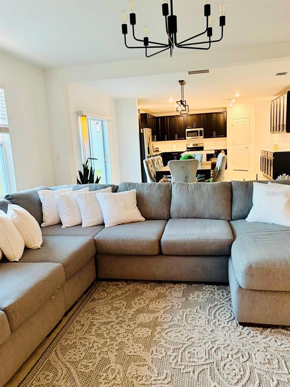 A gray sectional sofa sits on a patterned rug in an open-concept living area — 4220 BULL STREET, ST CLOUD, FL