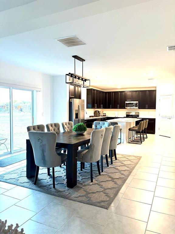A dining area with a dark wood table and gray chairs sits before an open kitchen — 4220 BULL STREET, ST CLOUD, FL