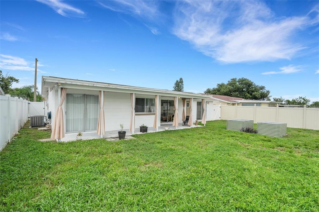 The exterior of a white, single-story house features a covered patio and a fenced yard — 7234 OAKSHIRE DRIVE, PORT RICHEY, FL