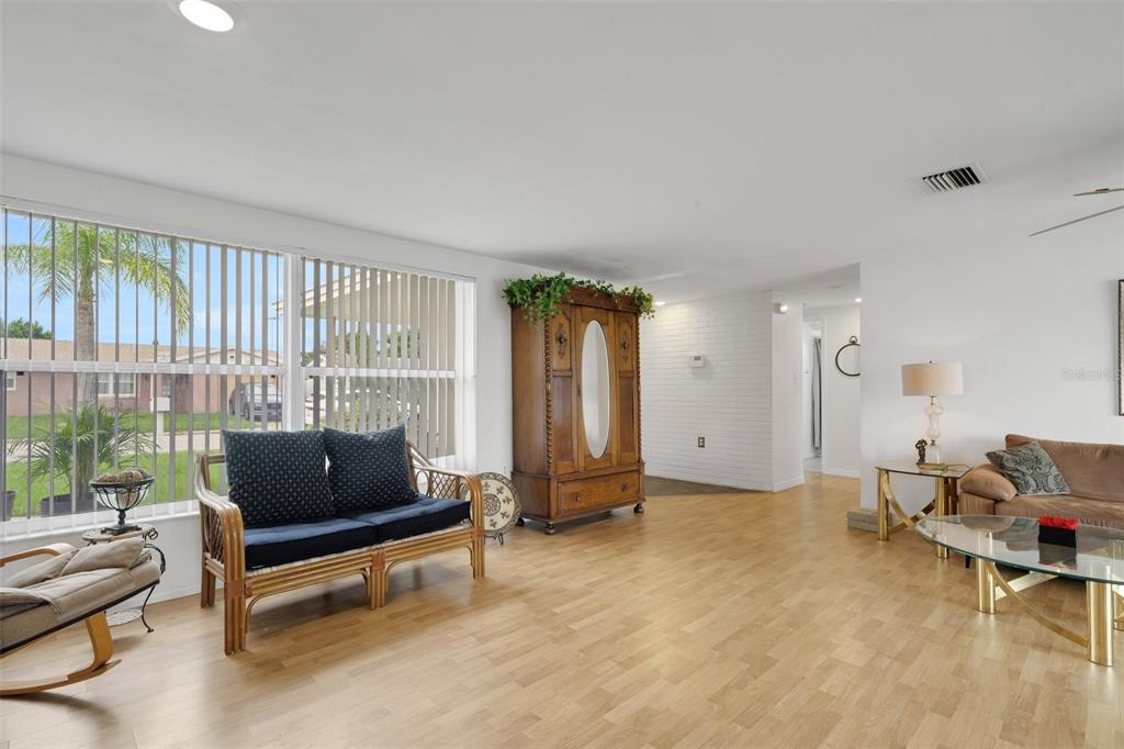 A living room with light wood flooring, a large wooden armoire, and a rattan sofa — 7234 OAKSHIRE DRIVE, PORT RICHEY, FL