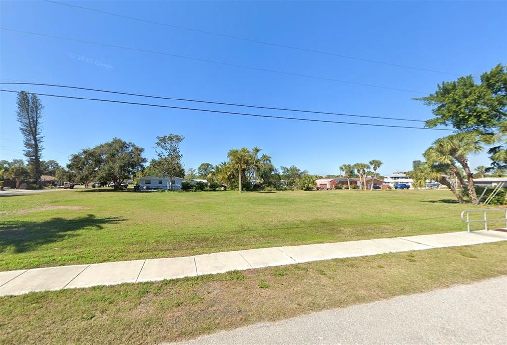 A large, flat, grassy vacant lot is bordered by a sidewalk and scattered trees — 510 BUENA VISTA DRIVE, NOKOMIS, FL