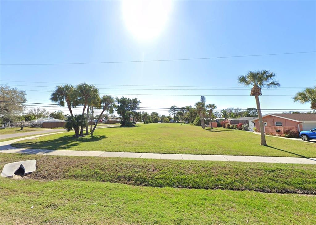 A vacant, grassy residential lot features a sidewalk and several palm trees under a bright sun — 510 BUENA VISTA DRIVE, NOKOMIS, FL