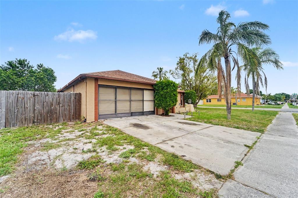 A single-story house with a screened garage, concrete driveway, and a wooden fence — 1215 PERSIMMON DRIVE, HOLIDAY, FL