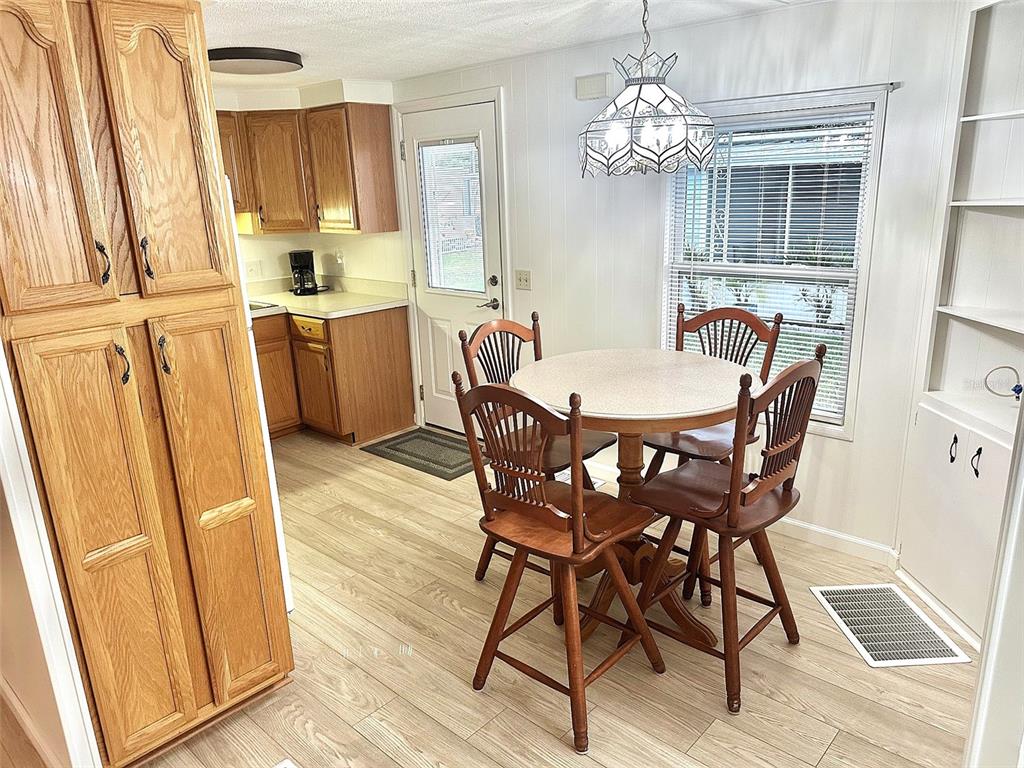 A dining area features a round table with four wooden chairs and a hanging lamp — 2000 E BAY DRIVE UNIT 83, LARGO, FL