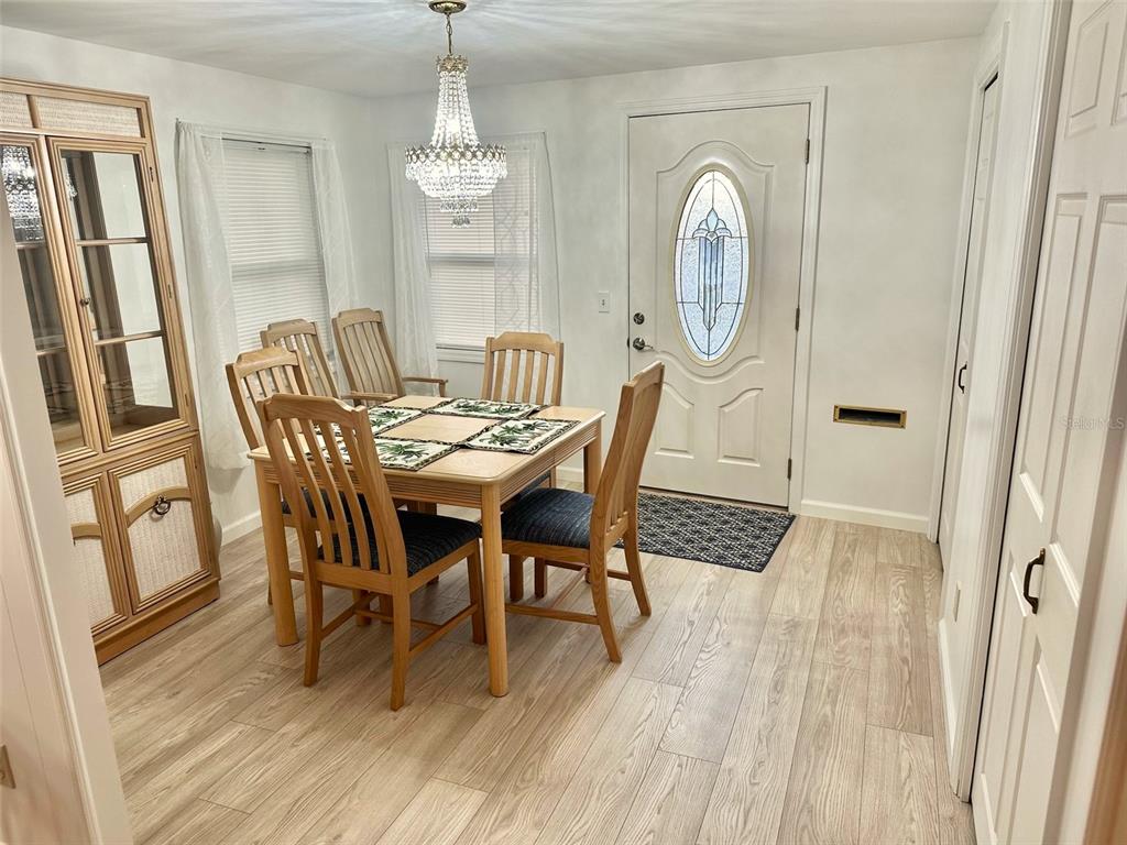 A dining room features a wooden table, four chairs, a crystal chandelier, and light flooring — 2000 E BAY DRIVE UNIT 83, LARGO, FL