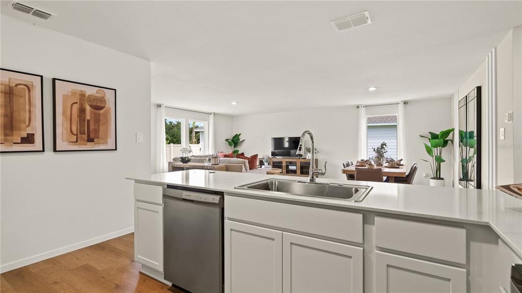A kitchen island with a stainless steel dishwasher and sink overlooks an open-concept living area — 6113 SWAMP BAY DRIVE, EDGEWATER, FL