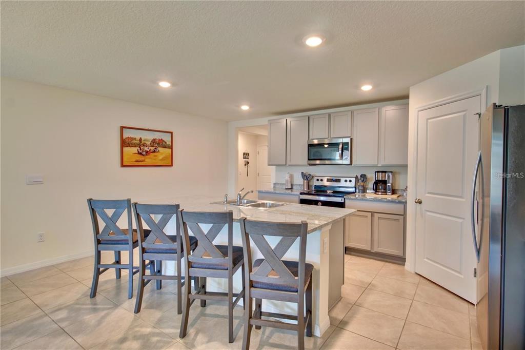 A kitchen features light gray cabinets, stainless steel appliances, and a central island with seating — 35712 DOVELAND DRIVE, ZEPHYRHILLS, FL
