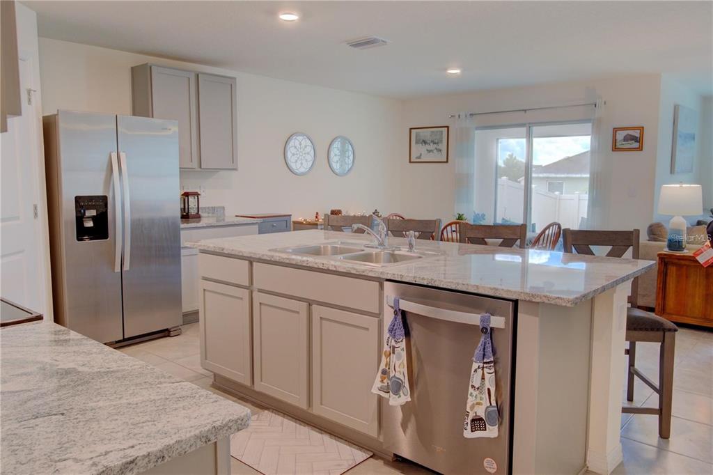 A kitchen features a granite-topped island, stainless steel appliances, and light-colored cabinetry — 35712 DOVELAND DRIVE, ZEPHYRHILLS, FL