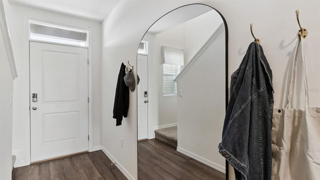 An entryway features a white door, an arched floor mirror, and wall-mounted coat hooks — 4294 BUTTERSCOTCH CIRCLE, LAKELAND, FL
