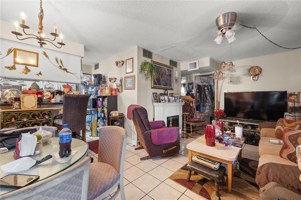 A living room and dining area featuring tile floors, a fireplace, and a ceiling fan — 4200 37TH STREET S, ST PETERSBURG, FL
