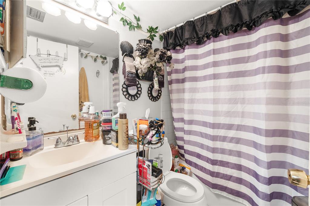A bathroom features a white vanity, a striped shower curtain, and a toilet — 4200 37TH STREET S, ST PETERSBURG, FL