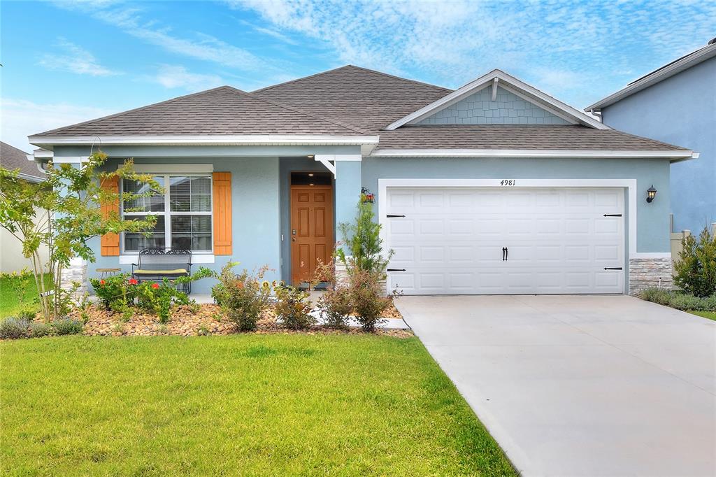 A blue single-story house with a two-car garage and a front lawn at sunset — 4981 FOXGLOVE CIRCLE, LAKELAND, FL