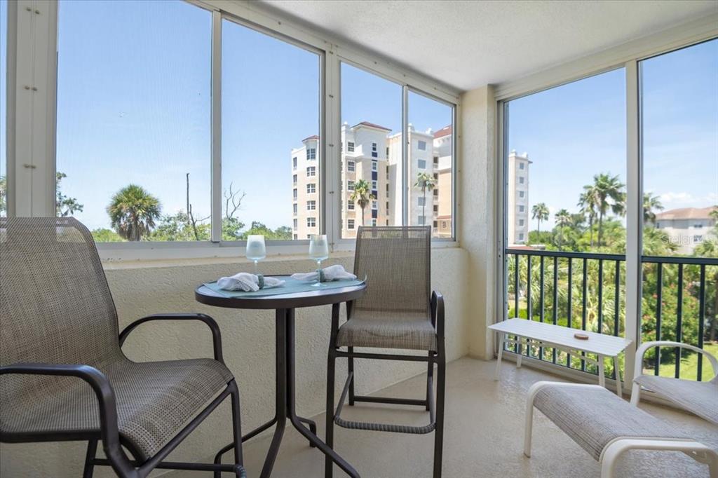 A screened-in balcony features a small table with two chairs and a view of buildings — 2625 TERRA CEIA BAY BOULEVARD UNIT 206, PALMETTO, FL